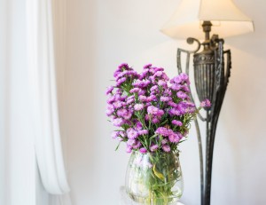 Purple flowers in glass vase for decoration in front of white wa