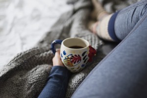 A woman drinking coffee while still in her pajamas in bed
